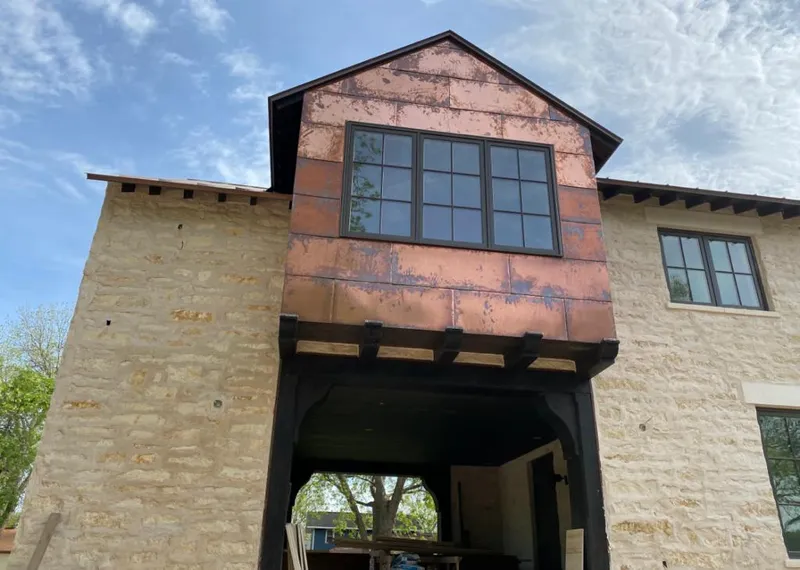 Copper metal panel facade on a stone building for Roof Repair in Iroquois Point